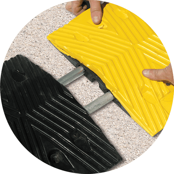 TreeTop Speed Bump with hands installing with steel rods on pavement” class=